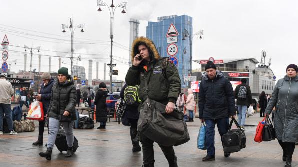 Des gens, certains portant des sacs et des valises, marchent près de la gare de Kiev-Pasazhyrskyi à Kiev dans la matinée du 24 février 2022. [Photo : DANIEL LEAL/AFP via Getty Images]